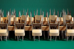 An infinite array of chairs and tables meticulously arranged in a school room.